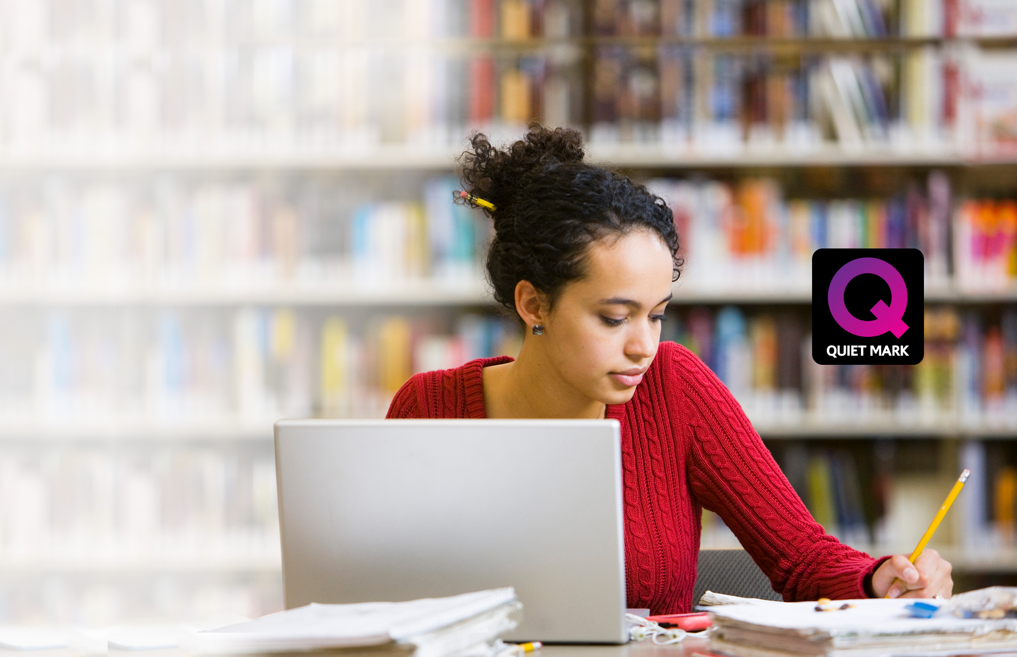 Girl sitting in library and writing on notepad.