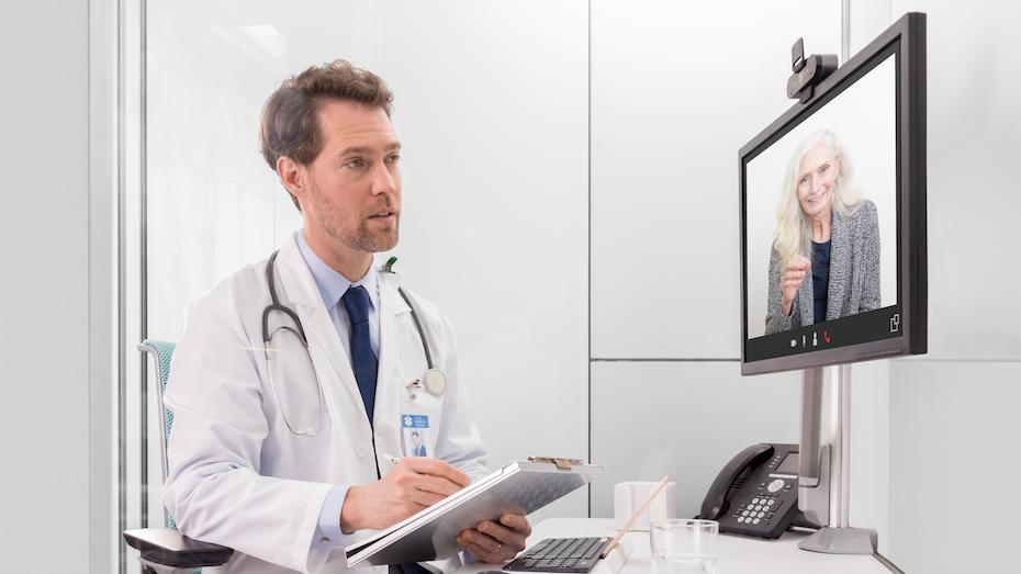 Arzt, der am Bildschirm mit Patient spricht