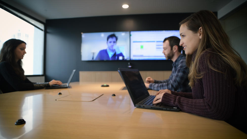 Pessoas em uma mesa de reuniões fazendo uma videoconferência