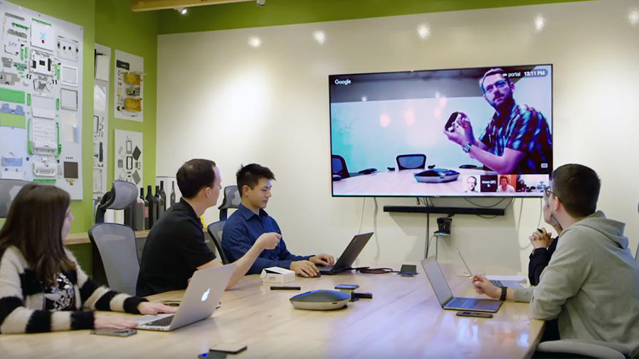 Pessoas em uma mesa de reuniões fazendo uma videoconferência
