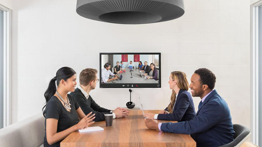 Pessoas em uma mesa de reuniões fazendo uma videoconferência