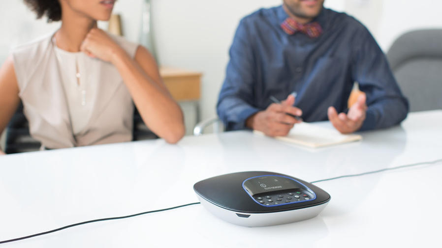 Pessoas em uma mesa de reuniões fazendo uma videoconferência