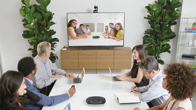Fotografia de um grupo em uma sala de conferência reunindo-se por videoconferência com outro grupo